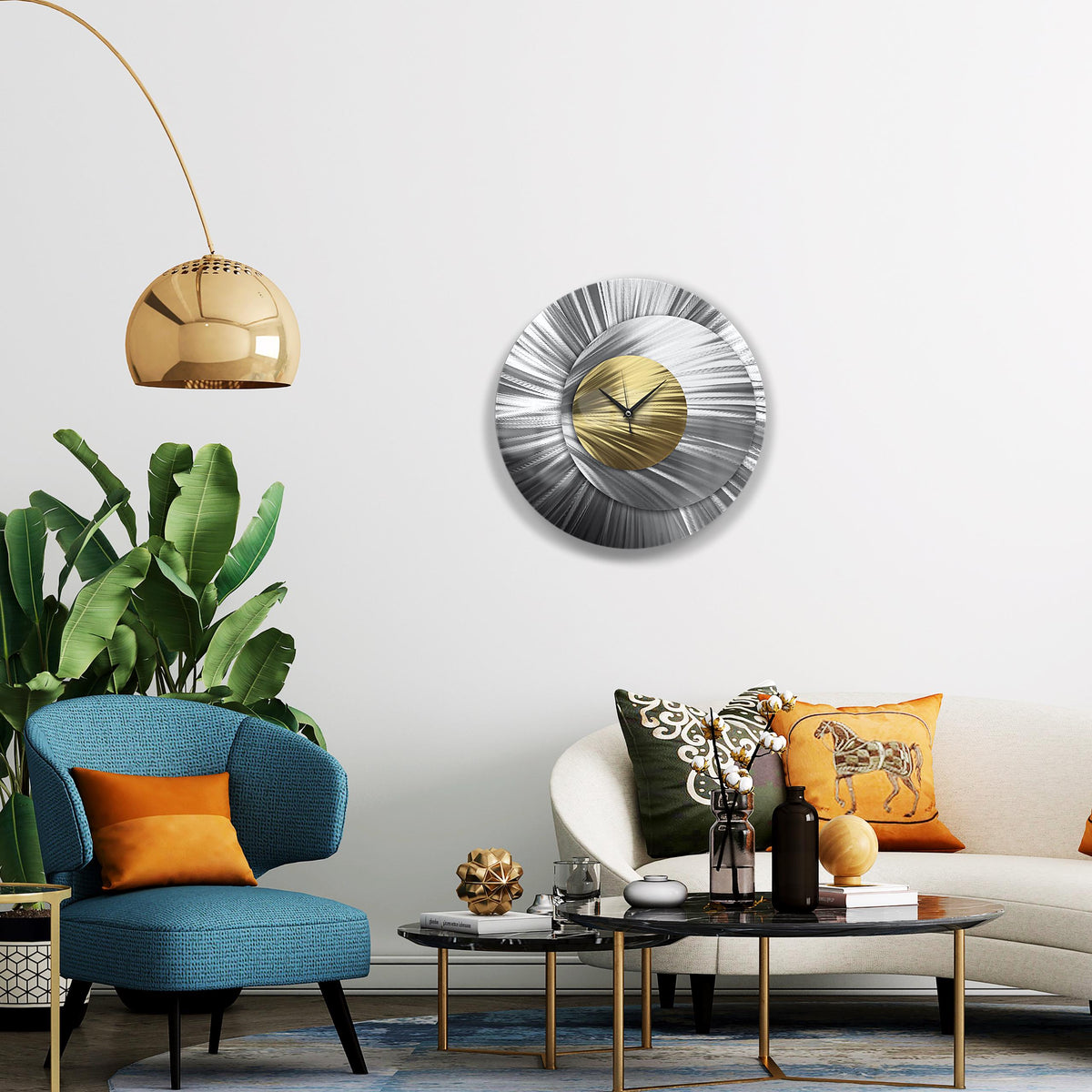 May include: A contemporary, circular wall clock with a silver and gold metallic finish. The clock has a radial design with a gold centre and silver outer ring. The clock is mounted on a white wall in a living room.