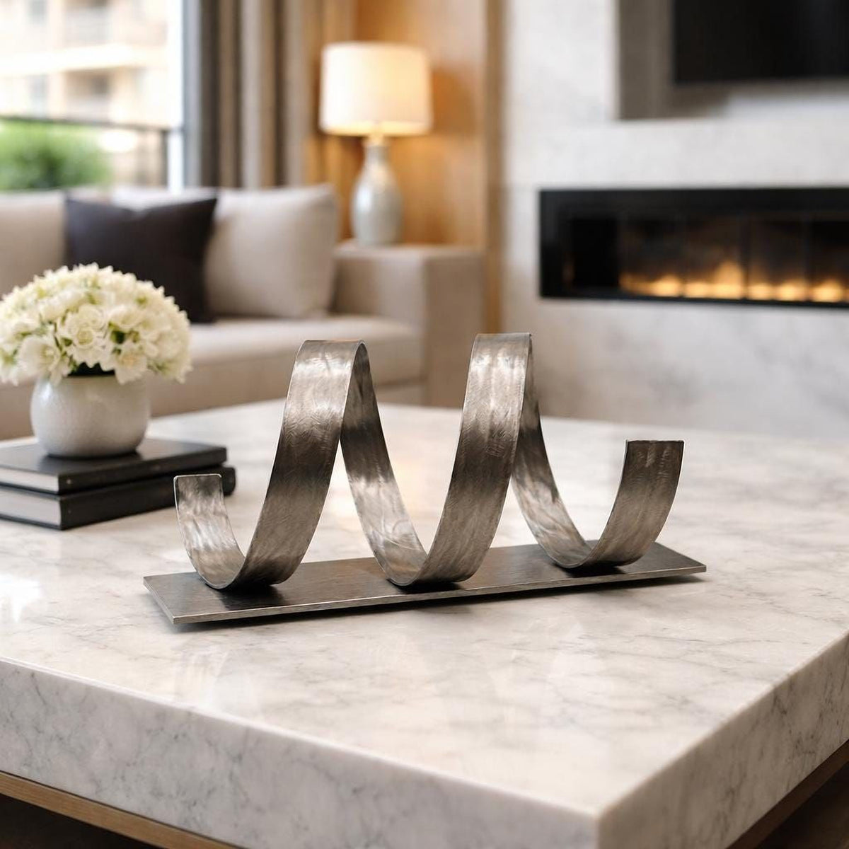 a modern living room with a marble table, a decorative metal sculpture, a lamp, and a fireplace.