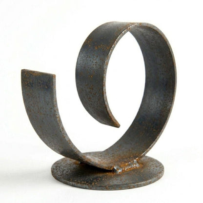 A spiral-shaped metal sculpture made of rusted metal, sitting on a round base.