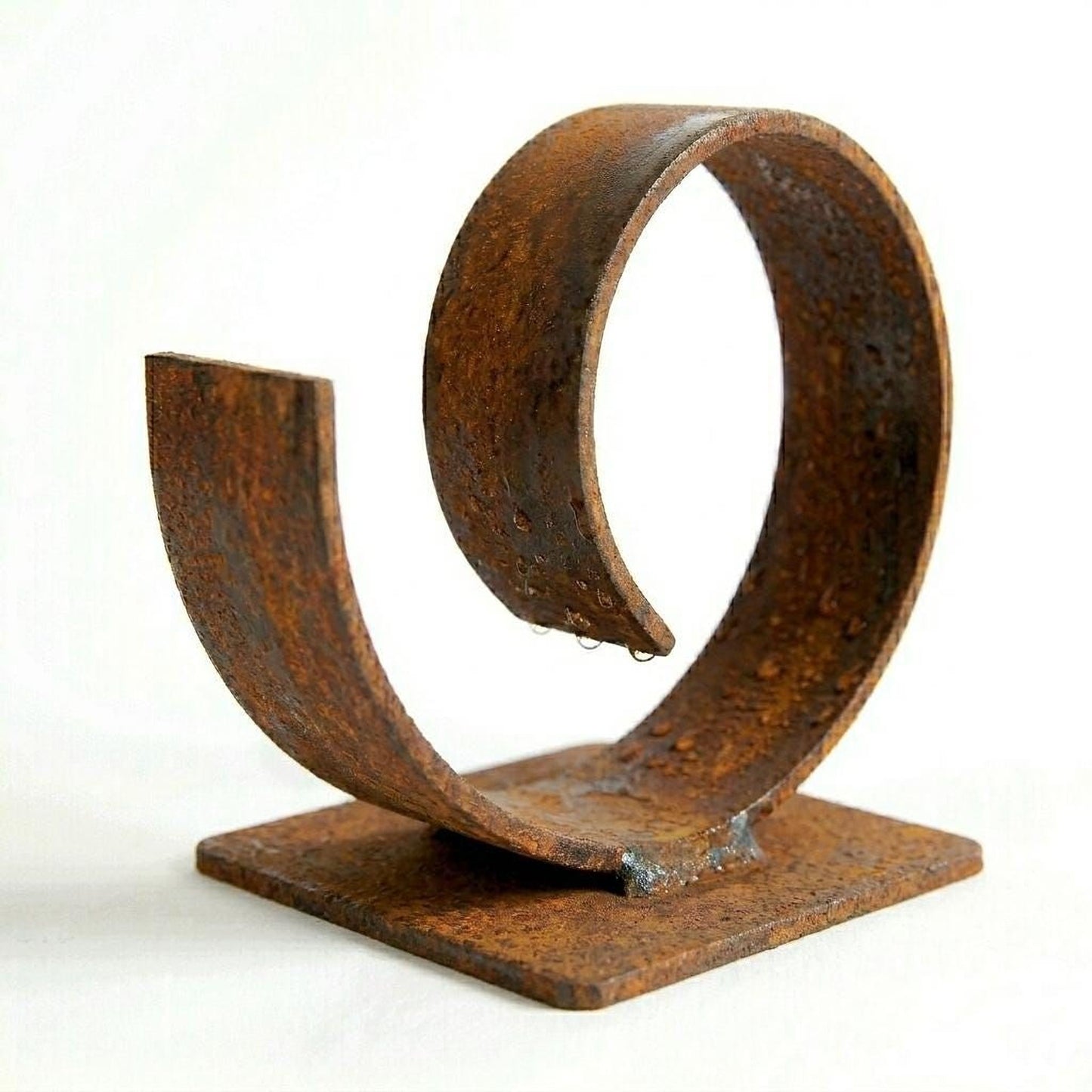 A rusted metal sculpture of a curved, metallic object with a textured surface.