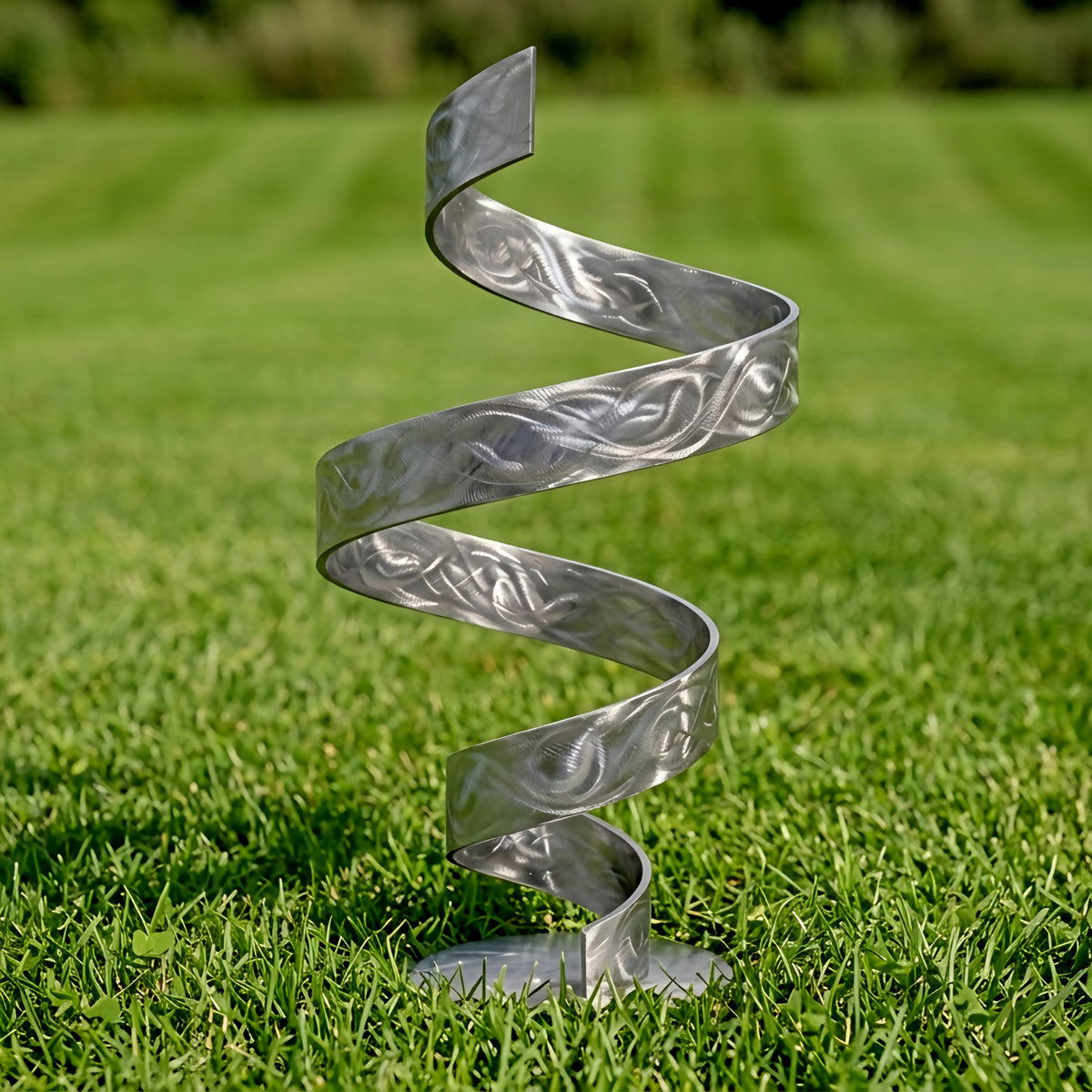 A metal spiral sculpture stands on a grassy lawn, its intricate design and curved form creating a visually striking contrast against the natural backdrop.