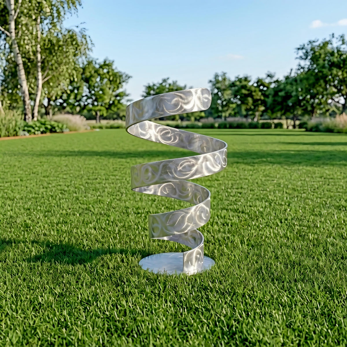 A silver spiral sculpture stands on a grassy lawn, surrounded by trees and shrubs.