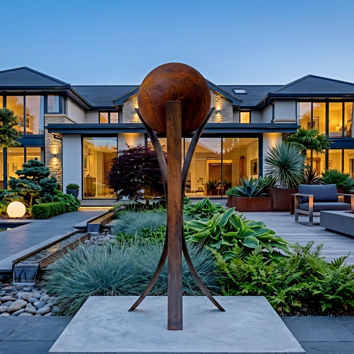 a large, modern house with a well-manicured garden in the foreground. The garden is adorned with various plants and a large, rustic sculpture that resembles a globe or ball. The house has a spacious deck and a pool, creating a serene and inviting atmosphere.
