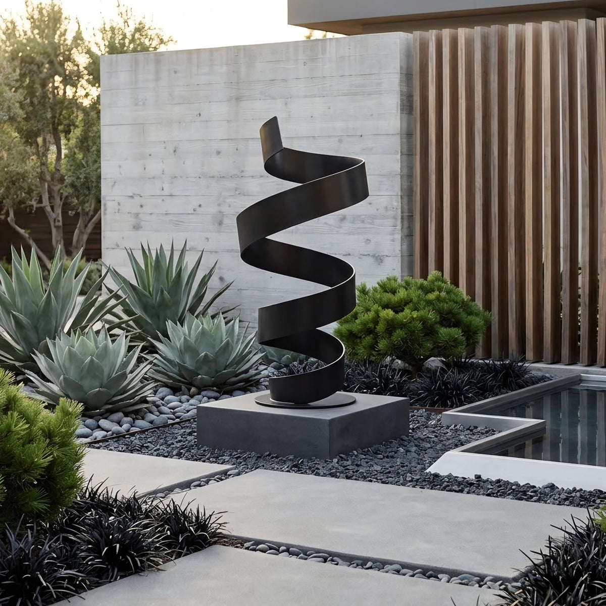 a modern garden design with a unique spiral sculpture as the centerpiece. The sculpture is made of black metal and is situated on a gray concrete base, surrounded by various plants and rocks. The garden is set against a backdrop of a wooden fence and a building, creating a harmonious and visually appealing outdoor space.