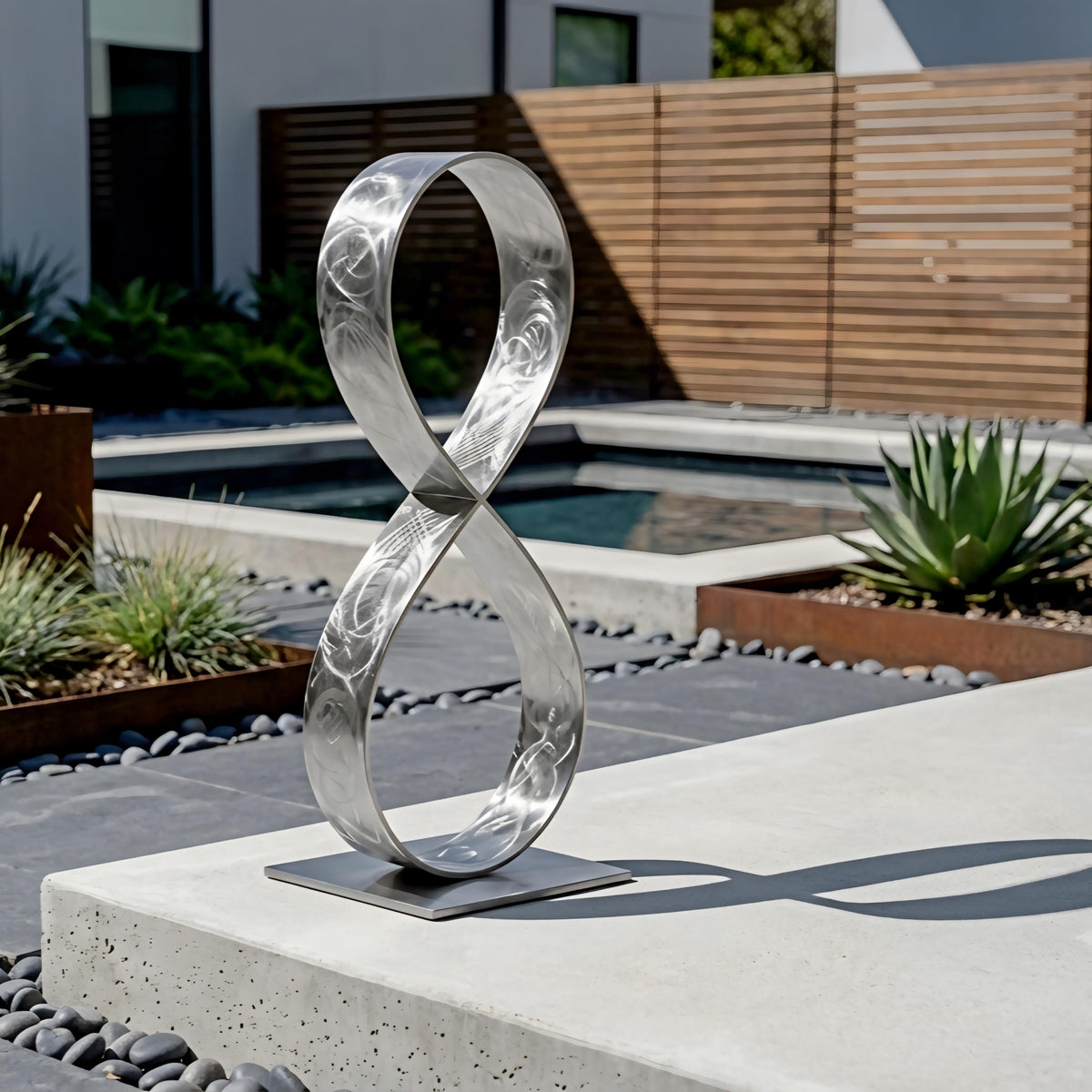 a modern outdoor sculpture composed of a metallic ring-like structure, placed on a concrete pedestal in a garden setting.