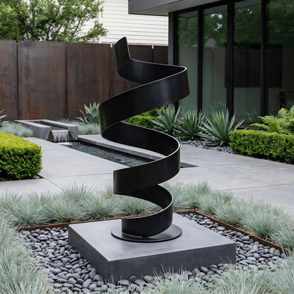 a modern black metal sculpture with a spiral shape, situated in a contemporary garden setting with a stone path, plants, and a glass building in the background.