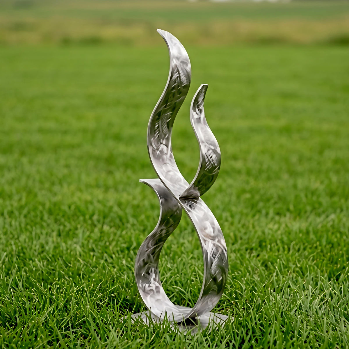 A metal sculpture resembling a flame or fire stands in a grassy field.