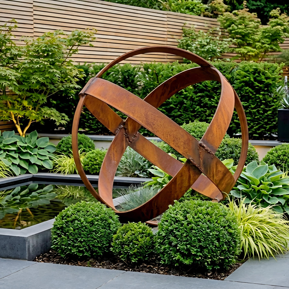 A large, rusted metal sculpture resembling an outer space object is situated in a garden, surrounded by lush greenery and a small pond.