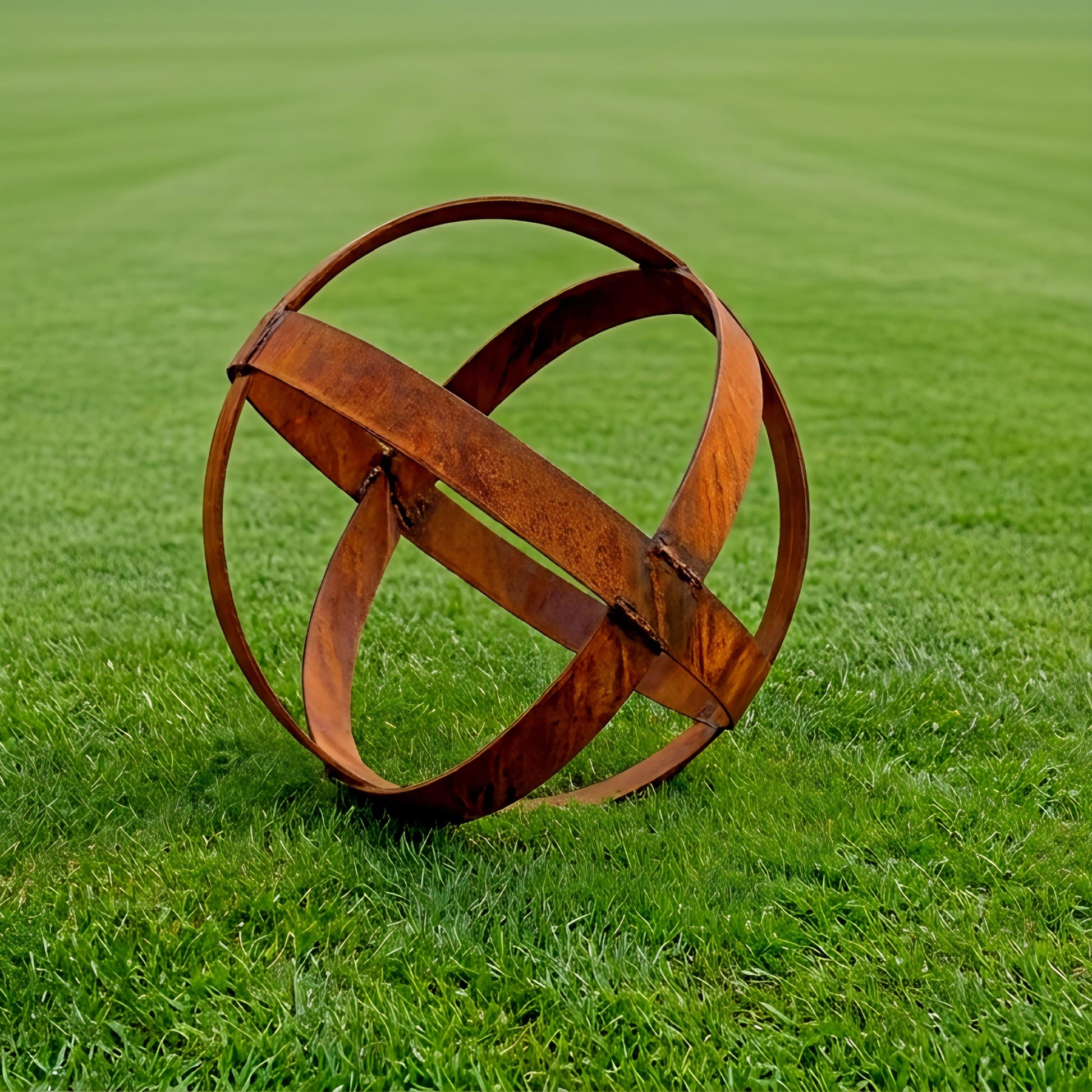 A rusted metal sphere sculpture stands on a lush green lawn.