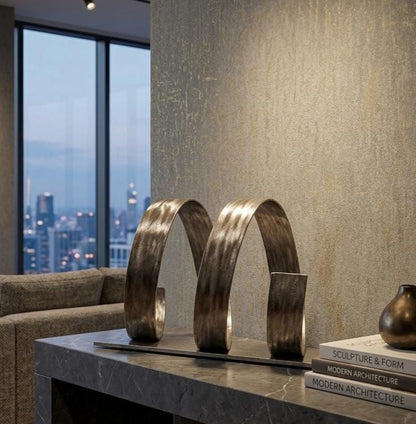 a modern living room with a large window overlooking a city skyline. The room has a gray marble countertop and a sculpture of two curved metal pieces, which appears to be a modern architectural piece. There are also some books on the countertop, suggesting a space for relaxation and intellectual pursuits.