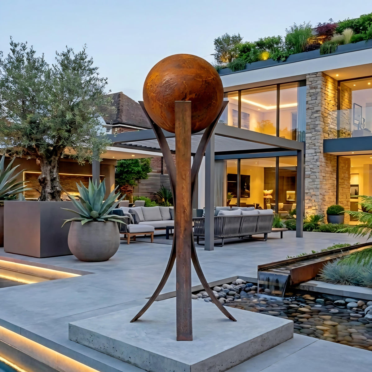a modern outdoor living space with a large, circular sculpture in the foreground, a stone building with a glass roof, and a pool with a waterfall feature.