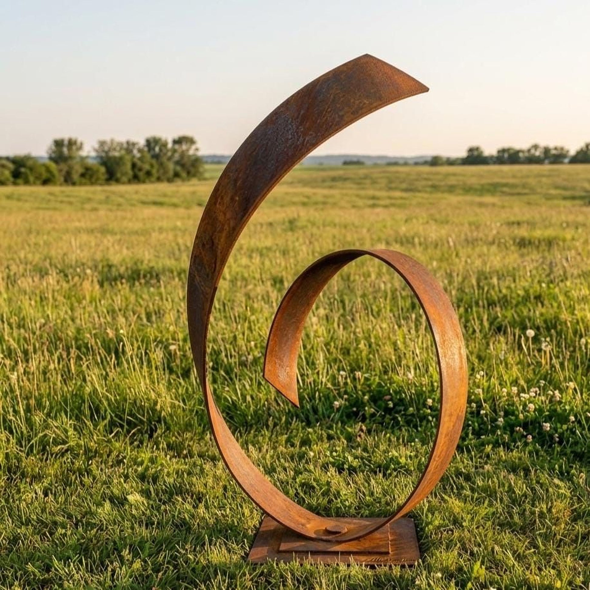 A large, abstract metal sculpture resembling a twisted, curving shape stands in a grassy field, with a clear blue sky in the background.