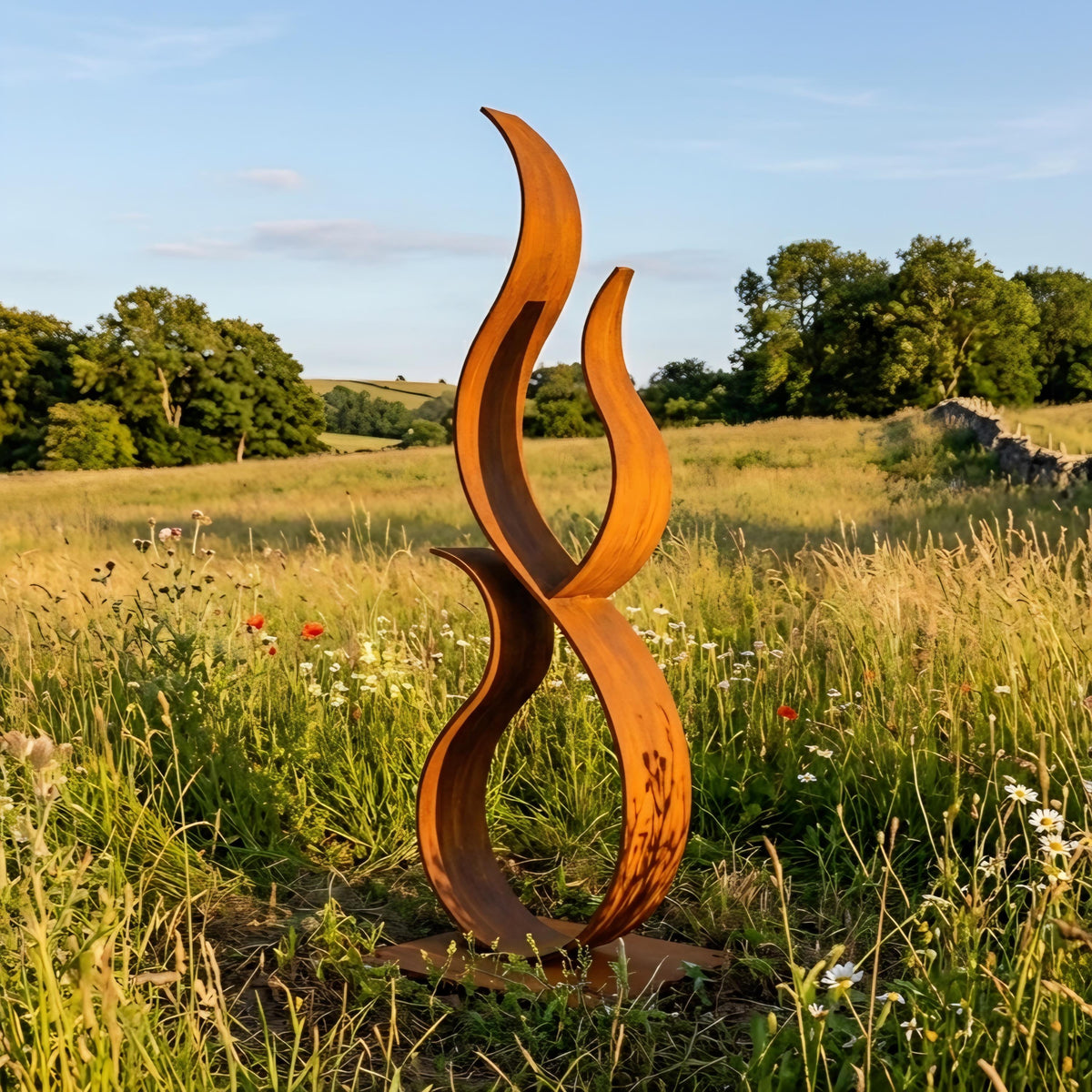 a large, abstract sculpture resembling a flame or fire, situated in a grassy field with trees and wildflowers in the background.