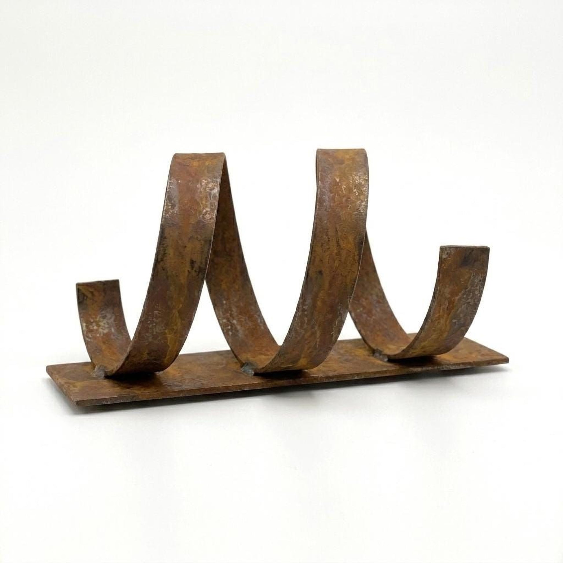 A rusted metal sculpture with curved, twisted shapes on a flat surface.