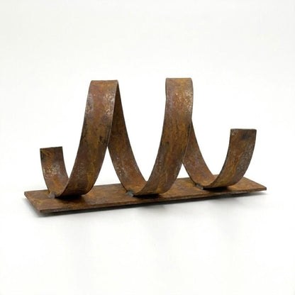 A rusted metal sculpture with curved, twisted shapes on a flat surface.