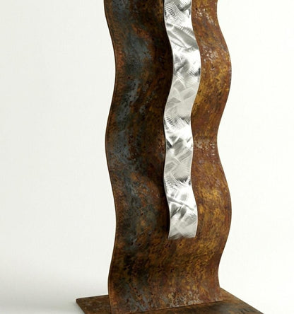 a sculpture with a metal ribbon or ribbon-like element attached to it, mounted on a rusted metal base.