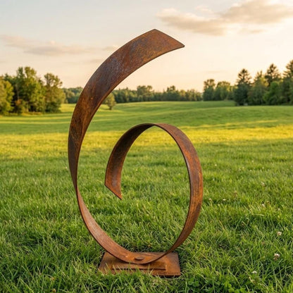 A large, rusted metal sculpture resembling a spiral or wave stands in a grassy field, with trees and a cloudy sky in the background.