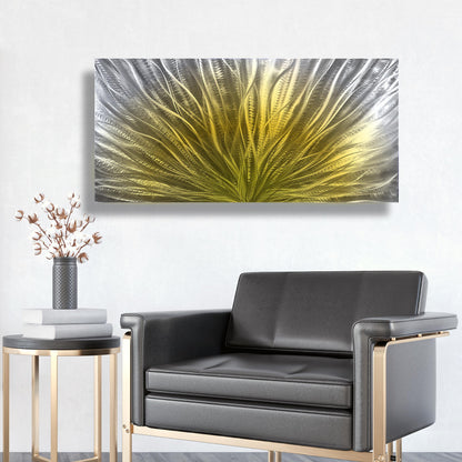 May include: A large, rectangular metal wall art piece with an abstract design. The artwork features a central burst of yellow, transitioning to silver and grey on the edges. It's mounted on a white wall above a black leather armchair.