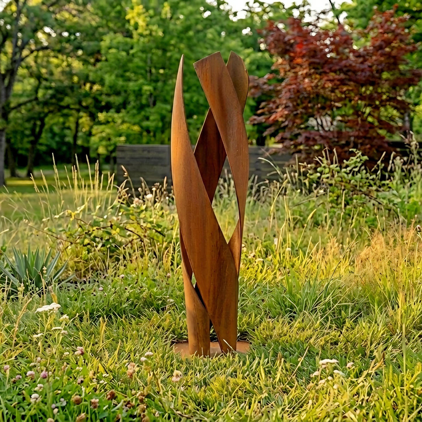 a large, abstract sculpture made of curved, brown metal pieces standing in a grassy area with trees and shrubs in the background.