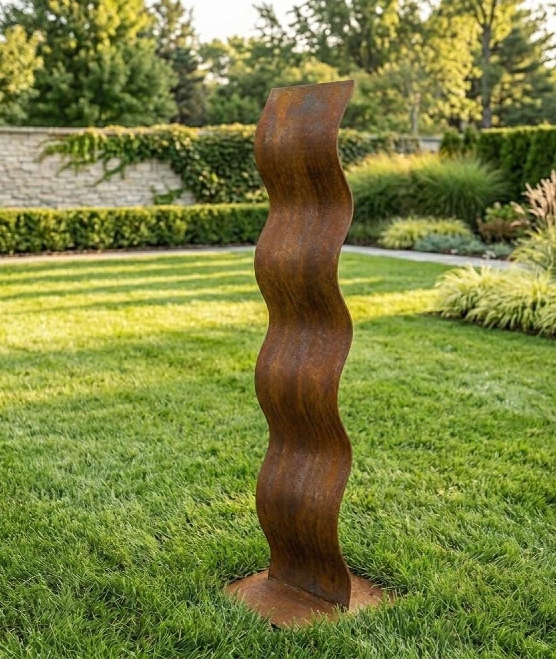 a tall, rust-colored metal sculpture standing in a lush, green garden.