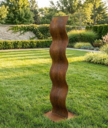 a tall, rust-colored metal sculpture standing in a lush, green garden.