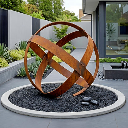 a large, abstract sculpture resembling a ring or an outer ring, situated in a circular planter with gravel and surrounded by various plants and rocks.