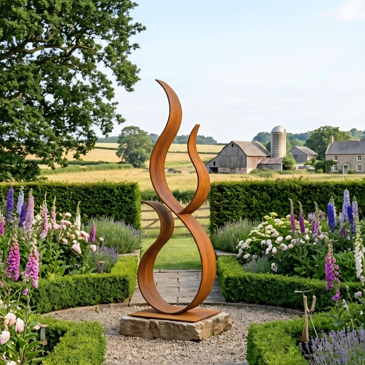 A large, abstract sculpture made of curved metal stands in a well-manicured garden, surrounded by colorful flowers and lush greenery. In the background, a farm with a silo can be seen, creating a picturesque rural setting.