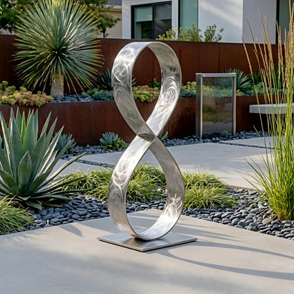 a modern garden sculpture of a metallic ring, surrounded by various plants and rocks.