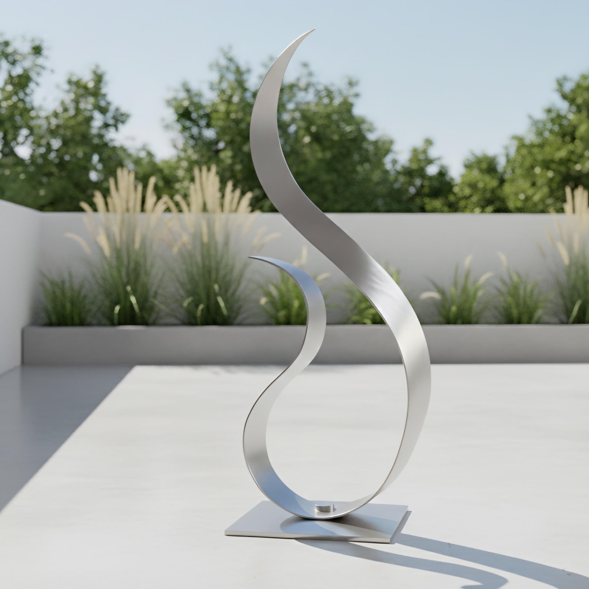 a modern, abstract sculpture composed of curved, metallic elements that resemble a flame or a wave-like shape. The sculpture is placed on a white surface, with a backdrop of greenery and a clear blue sky.