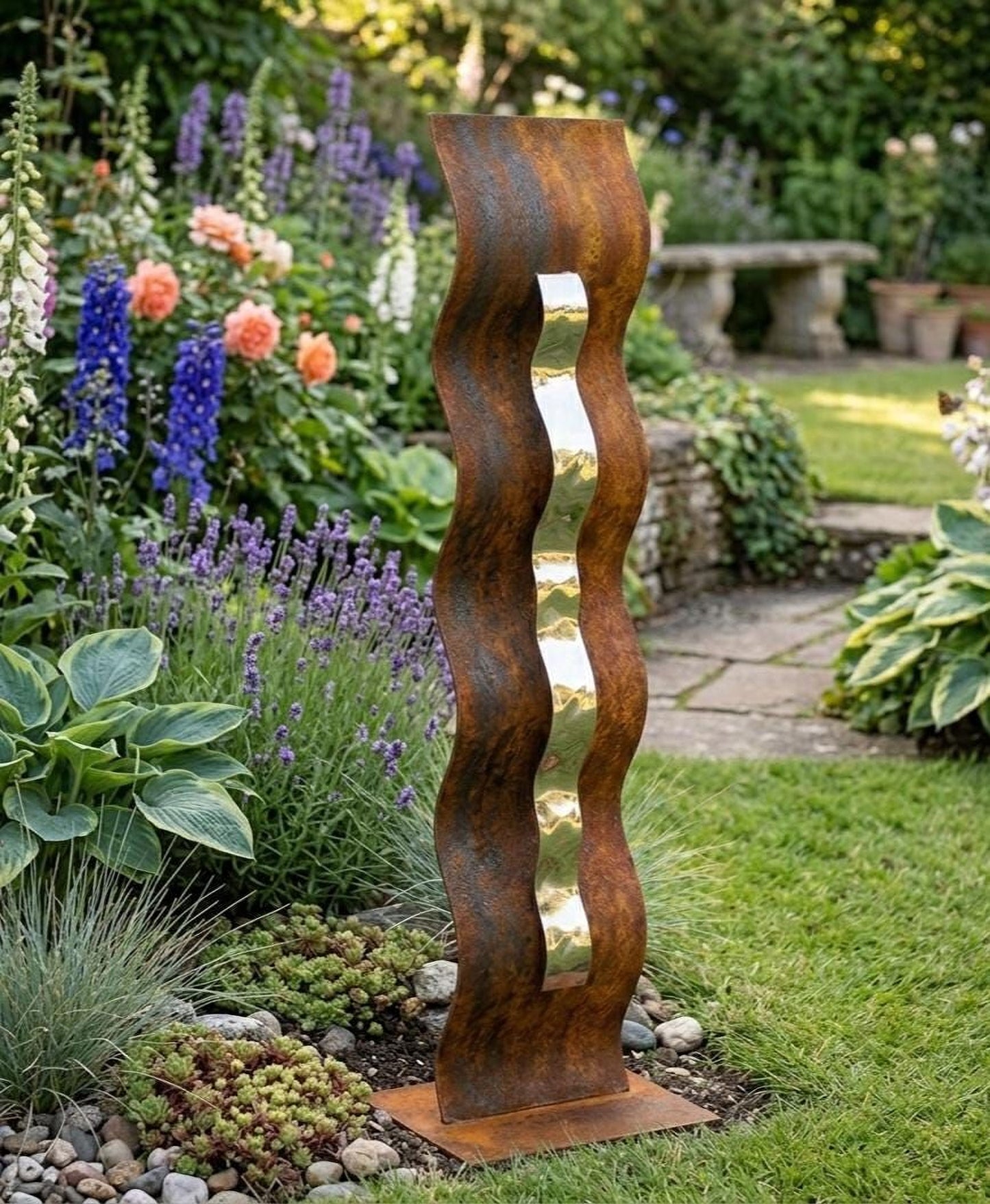 a tall, rust-colored metal sculpture with a vertical, wavy design, standing in a lush garden surrounded by various colorful flowers and plants.